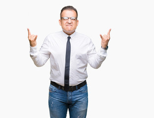 Middle age bussines arab man wearing glasses over isolated background shouting with crazy expression doing rock symbol with hands up. Music star. Heavy concept.