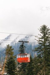 Red Ski lift in the background of the winter mountains. The red trailer of the old cable car moves to the mountain top of the ski resort. Retro gondola.