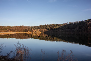 Herbstlicher See, mit Spiegelungen der Bäume im Wasser
