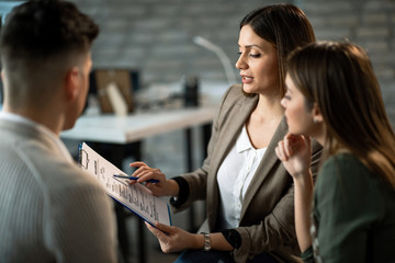 Young insurance agent reading terms of a contract to her clients.