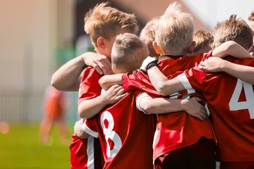 Fotobehang Kids Play Sports Game. Children Sporty Team United Ready to Play Game. Children Team Sport. Youth Sports For Children. Boys in Sports Jersey Red Shirts. Young Boys in Soccer Sportswear © matimix