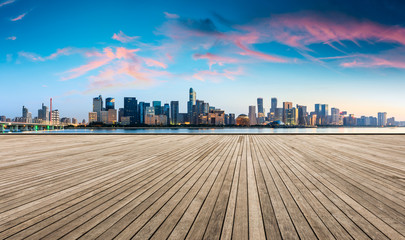 Obraz premium Empty wooden plank platform and Hangzhou city skyline at sunrise