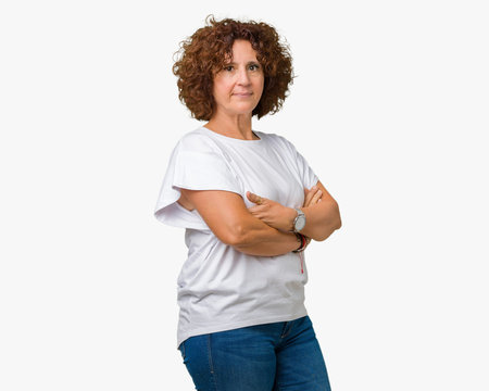 Beautiful middle ager senior woman wearing white t-shirt over isolated background Relaxed with serious expression on face. Simple and natural with crossed arms