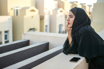 Side view portrait of beautiful young arab woman enjoying the view over city