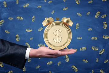 Man's hand with palm facing up to hold an alarm clock with a stylized dollar coin instead of clock face on blue background with lots of hand-drawn coins.
