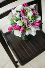 Bridal bouquet in focus black wooden seat.