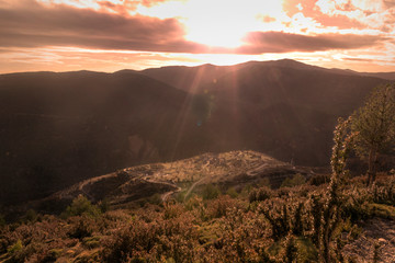 cielo al atardecer en la montaña. Los ultimos rayos de sol iluminan el pequeño pueblo en la colina
