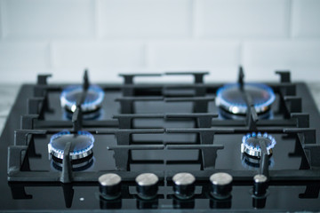 Fototapeta na wymiar Cooktop with burning gas ring. Gas cooker with blue flames.