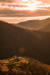 Cielo al atardecer en las montañas. Ultimos rayos de sol iluminan en pequeño pueblo de la colina