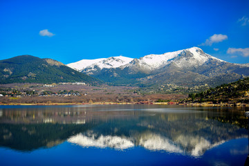 Montañas nevadas reflejadas en un lago azul de aguas tranquilas en un dia soleado de primavera