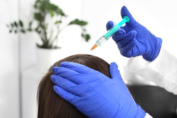 Obraz premium Ostrzykiwanie skóry głowy. Kobieta w gabinecie lekarskim na zabiegu.