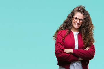 Beautiful brunette curly hair young girl wearing jacket and glasses over isolated background happy face smiling with crossed arms looking at the camera. Positive person.