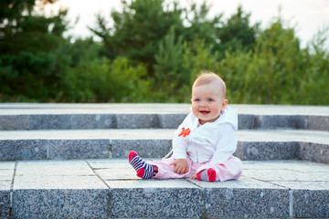 A small child sits on the ground and laughs.