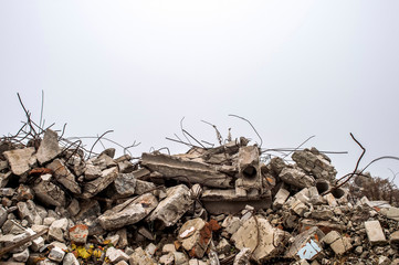 The rebar sticking up from piles of brick rubble, stone and concrete rubble against the sky in a...