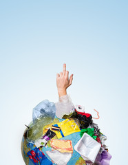 Obraz premium An earth globe covered with trash and male hand showing middle finger over white background, the concept of ecology problem and World Environment Day. Photo with message for social advertising, place