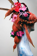 Mannequin in creative wig with flowers and feathers 