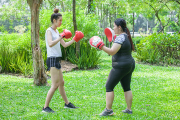 beautiful Young sport girl training boxing in red gloves with fat trainer woman exercise in the...