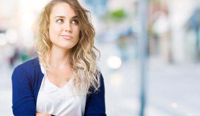 Beautiful young blonde woman over isolated background smiling looking side and staring away thinking.
