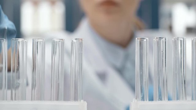 cropped view of female scientist choosing glass tube in lab