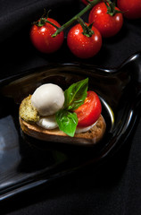 The author's presentation of bruschetta with cream cheese, mozzarella, cherry tomatoes and greenery on a dark stylish background