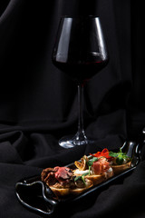 Trio of bruschetta with a red wine on dark stylish backround
