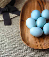 Easter eggs colored in light blue in a wooden plate.