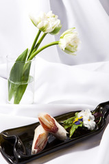 Springrolls with ham, pear and white tulips on a white stylish background