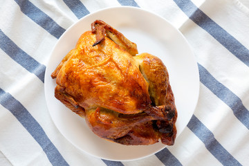 Homemade tasty rotisserie chicken on white plate, top view. Flat lay, overhead, from above.