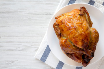 Homemade tasty rotisserie chicken on white plate, top view. Flat lay, overhead, from above. Copy space.