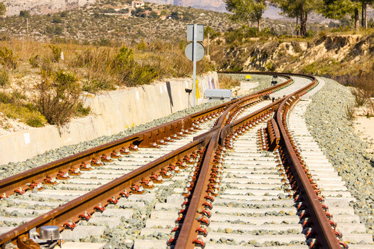 A railroad switch track with traffic signs, mountains and trees in the background