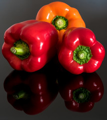 Three bell peppers on a reflective surface