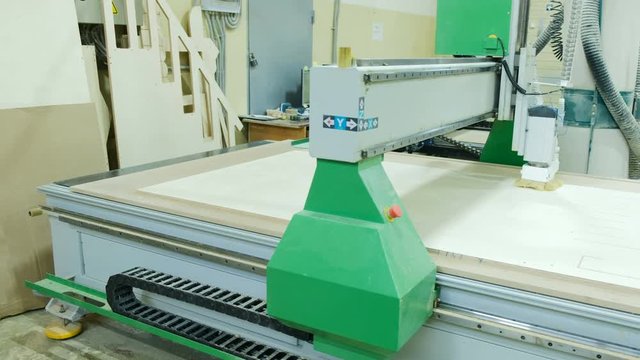 Automatic woodworking machine cuts out details on a wooden panel, modern woodworking machine cnc