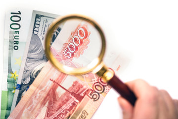 Five thousand russian rubles  under a magnifying glass on the bacdrop euro and usa dollar. Сoncept...