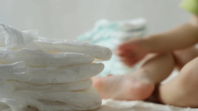 Child plays with baby diapers in a pile, baby, background, diaper