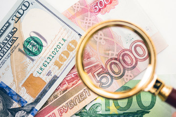 Five thousand russian rubles  under a magnifying glass on the bacdrop euro and usa dollar. Сoncept of the main international currency