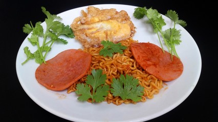 Thai spicy Yellow noodles , minced pork, tofu .. Sprinkle with coriander ... Put in a white dish. With a black background.