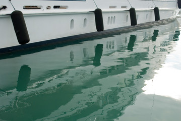 detail photo of a yacht, keel, fenders, reflection in the water of the harbor or marina, sunset, holidays, travel, mediterranean, background, Imperia, Liguria, Italy