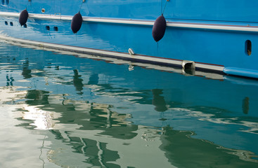 detail photo of a yacht, keel, fenders, reflection in the water of the harbor or marina, sunset, holidays, travel, mediterranean, background, Imperia, Liguria, Italy