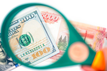 Hundred dollar under a magnifying glass on the bacdrop euro and ruble banknotes. Сoncept of the main international currency