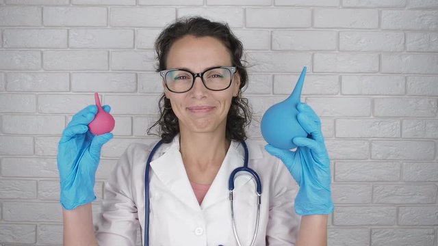 Woman doctor with enemas. Cheerful woman doctor with medical pears.
