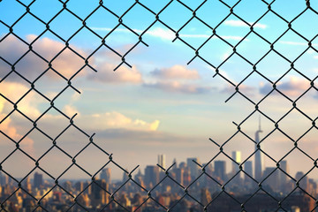 View on the New York city through the hole of steel mesh wire fence. Concept