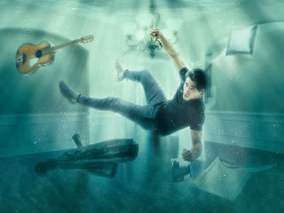 Fototapeta na wymiar Illusion of man floating underwater among objects in room looking at camera 