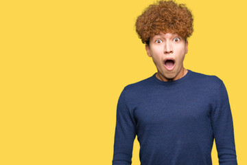 Young handsome man with afro hair In shock face, looking skeptical and sarcastic, surprised with open mouth