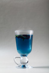 Blue tea Anchan in an Irish glass on a gray background. Cup of Butterfly pea tea, pea flowers, blue pea. Healthy, detox