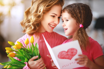 happy mother's day! child daughter   gives mother a bouquet of flowers and postcard.