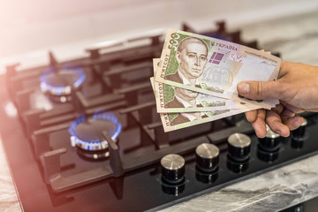 Ukrainian hryvnia on a gas hob with burning natural gas. The concept of the problem of gas...
