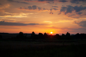 Naklejka na ściany i meble View of a Beautiful Sunset and Sky with dramatic clouds over a Silhouetted Land Horizont.