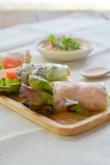 Salad roll with Green and red oaks, slice carrot, sausage, tuna on wooden tray with spicy dipping (Chili, Garlic and fish sauce). Healthy food.