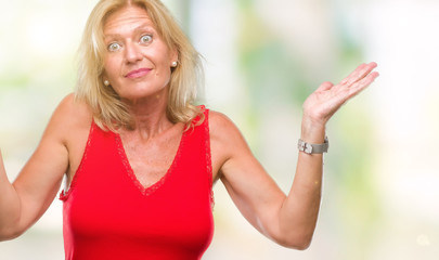 Middle age blonde woman over isolated background clueless and confused expression with arms and hands raised. Doubt concept.
