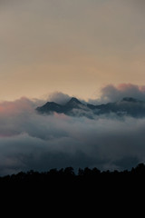 alpine landscape with peaks covered by snow and clouds. sunset